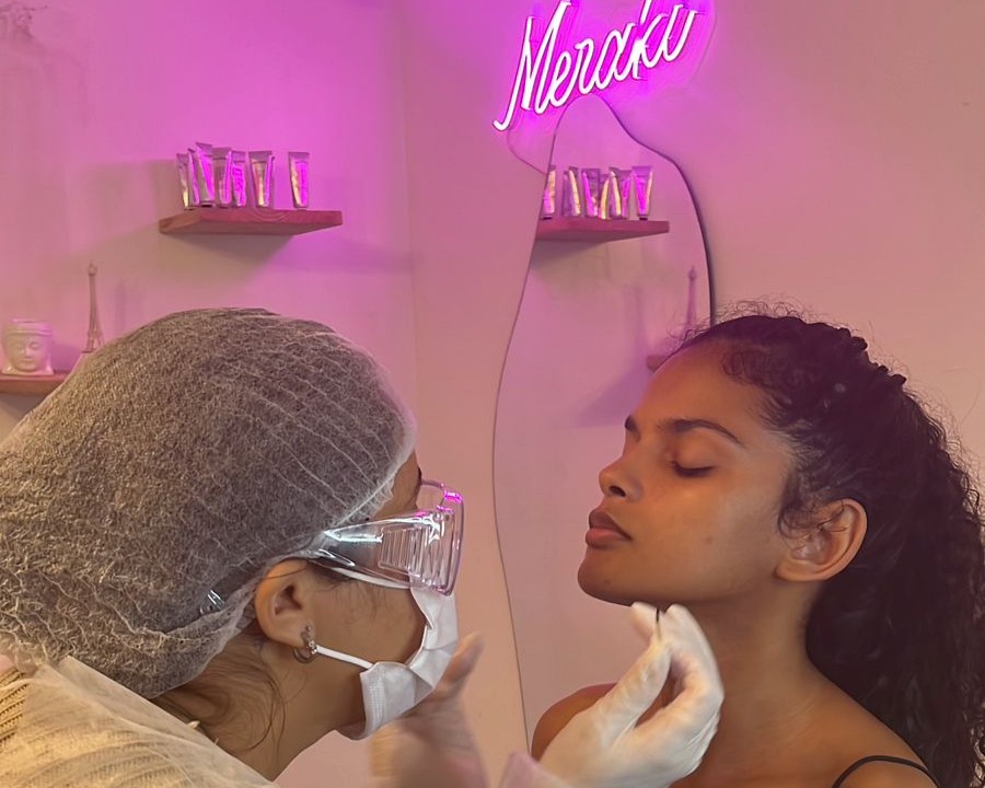 Body piercer do Meraki Tattoo realizando uma perfuração facial em uma cliente